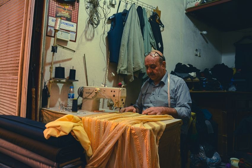 Maker sewing detailed golden fabric in a traditional workshop