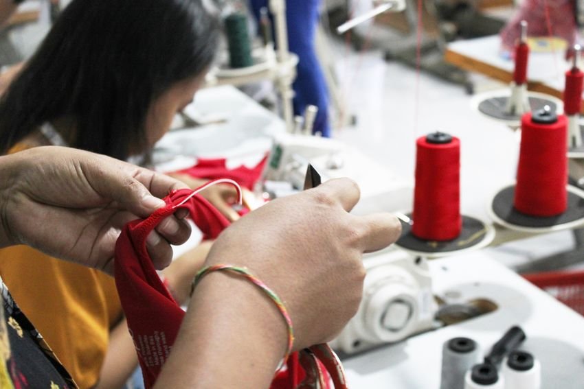 Close view of careful hand-finishing beside a sewing machine